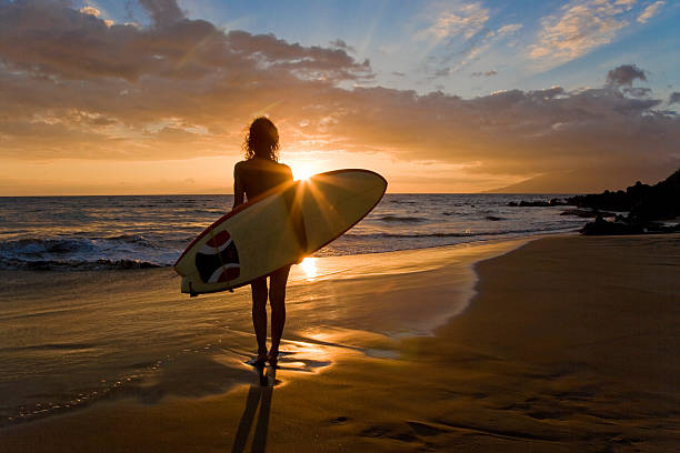 Surfer girl silhouette with surfboard in south Maui, Hawaii, USA.