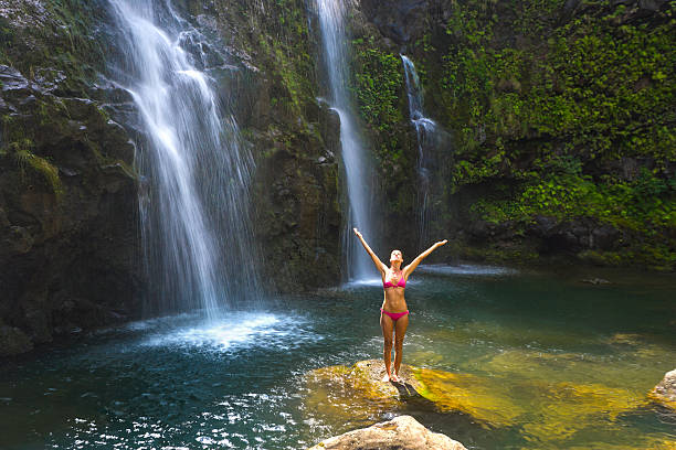 woman enjoying waterfall in Maui, Hawaii.